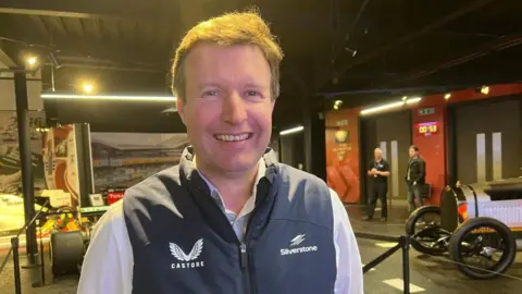 Stuart Pringle in a shirt and gilet looking at the camera and smiling