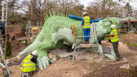 Historic England Archive Three people in high-visibility jackets paint a sculpture of a Hylaeosaurus, meaning forest lizard.