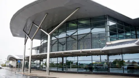 BBC The outside Guernsey Airport, a modern-looking, glass-front building.