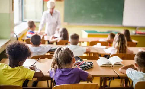 Getty Images Rear view of elementary students attending a class in the classroom. - stock photo