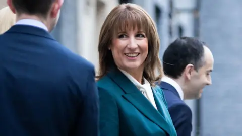 PA Media Rachel Reeves on teh day of the budget looking at a colleague whose back is to the camera and she is smiling