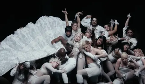 Interscope / Lady Gaga A still from Lady Gaga's Abracadbra video, showing the star with dozens of dancers in a baroque pose