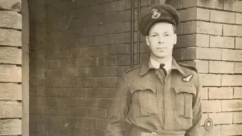 Black-and-white archive image of an airman in uniform. He is young and is wearing a cap bearing an emblem.