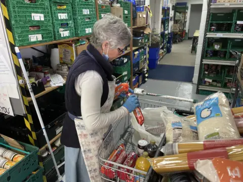 Alex Dunlop/BBC A woman sorting out food at a Suffolk charity 
