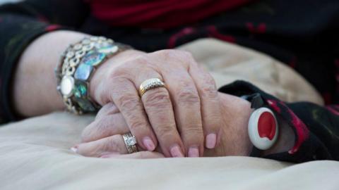 File image of a woman wearing a wrist alarm consisting of a black band, white unit and red button