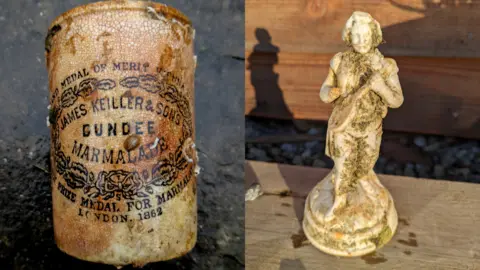 Dom Robinson Jar of marmalade with barnacles and a white statue of a person with seaweed on it