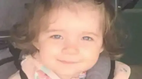 supplied Head-and-shoulders image of Isabelle Rose Welsh. She is a two-year-old girl, is smiling directly into the camera and has dark curly hair. She is wearing a pink top.
