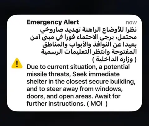 Mic Cassidy A text alert message in Arabic an English advising travellers to seek shelter inside secure buildings and to stay away from windows