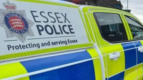 A police vehicle: The words "ESSEX POLICE Protecting and serving Essex" written in blue on the side of a yellow and blue coloured vehicle