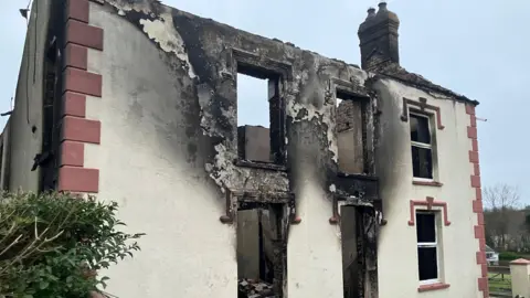 BBC House badly damaged by fire in Drefach, with scorch marks outside some windows and the front door and on the exterior walls