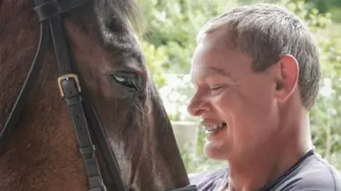 Penguin Books Martin Clunes smiling at his horse Chester