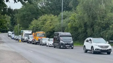 A queue of traffic on the road next to Dalscone Farm.