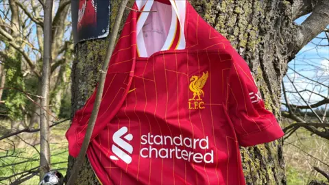 Richard Knights/BBC A red Liverpool football shirt propped up on a tree.