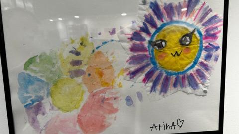 A painting featuring a sun and a flower