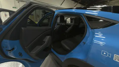 A blue car has its doors open