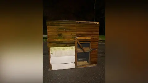 BCH Road Policing Unit Wooden chicken coop on a tarmac road during the night. 