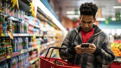 Man looking at smartphone in supermarket