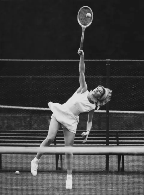 Getty Pericoli serves in a white dress and scarf 