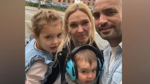 Family handout A family of a man and woman with two young children, a girl with light curly hair and a baby with blue ear defenders on 