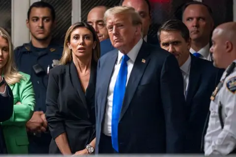 Getty Images Donald Trump's lawyer Alina Habba (L) reacts as former US President and Republican presidential candidate Donald Trump walks to speak to the press after his arraignment in Manhattan Criminal Court.