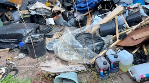Hassan's back garden is covered in plant pots, growing solution, seed trays, black plastic bags and broken up bits of furniture