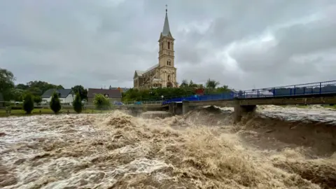 Potok wody przepływa wzdłuż rzeki Bila podczas ulewnego deszczu w Mikulovicach w Czechach.