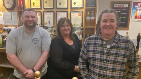 Bar manager Sean Rowbottom, events coordinator and licensee Lisa Moody and cellarman Tony Hill inside the Billingham Catholic Club. They are pictured behind the bar, and behind them are lots of framed CAMRA awards.