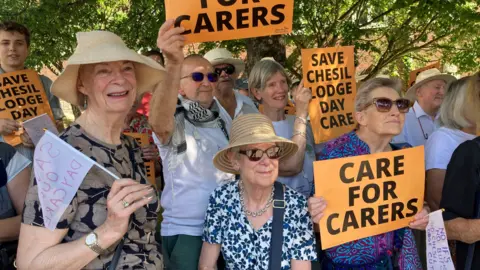 Groups of protestors holding care for carers posters