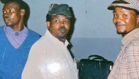 Mzolisi Dyasi Mzolisi Dyasi, flanked by two friends, wears a white jacket and green cap as they travel to a funeral of a political activist in 1993