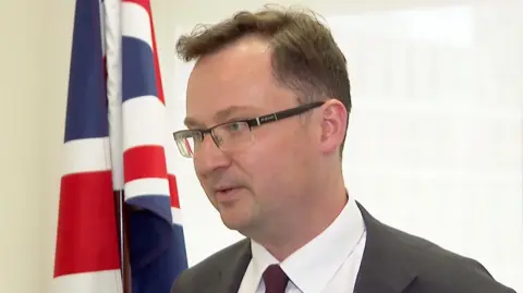 Alex Norris stands in front of a Union flag