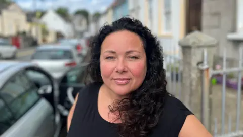 A woman wearing a black top with black curly hair