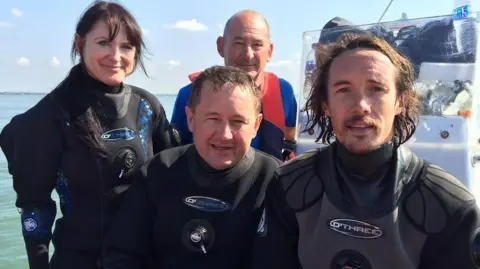MSDS Marine A woman and two men in diving suits with a third man behind in a boat in the Thames Estuary in 2014