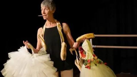 Alexandra Pickford Alexandra Pickford is standing on a stage holding two white ballet tutus.