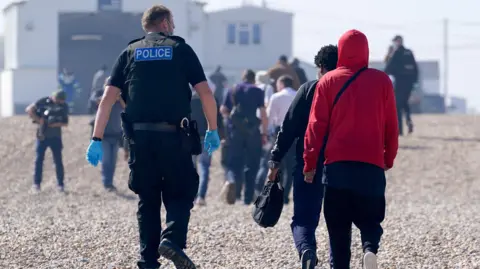 A group of people thought to be migrants are brought ashore from the Dungeness lifeboat in Dungeness, Kent, after being picked-up following a small boat incident in the Channel in 2021. 