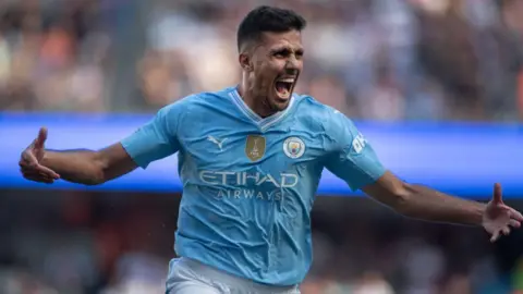 Man City midfielder Rodri celebrate with arms out wide