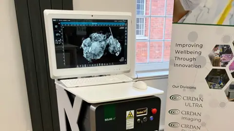 A machine with a white monitor on top of it and a poster next to it.