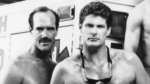 Everett/Shutterstock Michael Newman and David Hasselhoff stand shirtless together in Baywatch