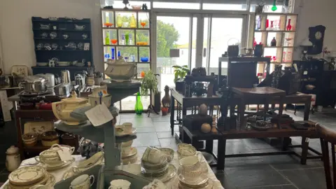 A large showroom with lots of pieces of furniture and crockery on show