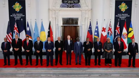 Getty Images US President Joe Biden (C) and leaders from the Pacific Islands region pose for a photograph on the North Portico of the White House September 29, 2022 in Washington DC. Behind them is a row of flags of the various countries present.  