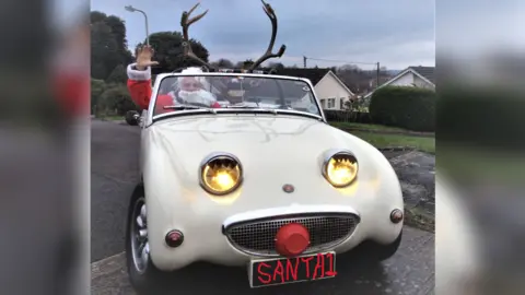 Children's Hospice South West A 1979 MG Midget Frogeye Sprite replica with antlers attached to the front, and Robin in the driver's seat dressed as Santa Claus