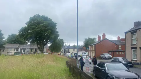 People gather outside the police cordon, with the damaged pub in the background