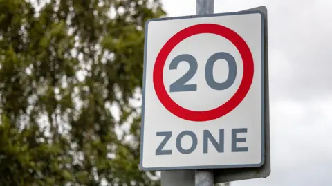 Red circle road safety suburban slow traffic calming sign with 20mph speed limit restriction zone street sign - stock photo