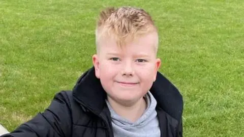 Louise Fox A child, George Fox, wearing a black coat and smiling at the camera.