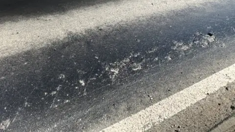 Richard Daniel/BBC A close up of a tarmacked road where parts are melting.