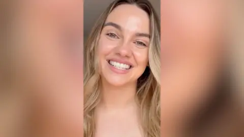 A blonde woman smiles.