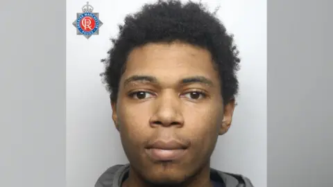 A mugshot of Leon Blackett who is staring forward and wearing a grey hoodie. 