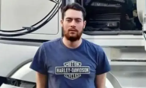 North Yorkshire Police Gregory Newcombe wearing a blue t-shirt and stood in front of a lorry