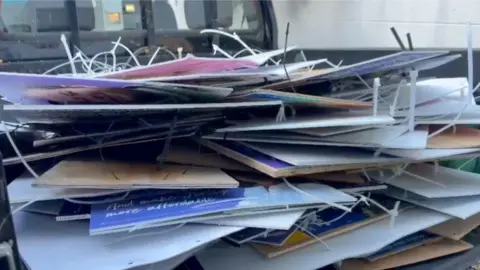 A pile of election posters piled in the back of a flat-bed truck. Many have cable ties attached.