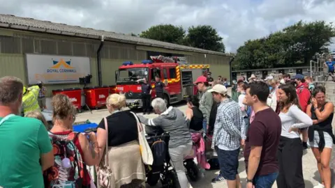 A group of people stood in front of fire engine outside of a building. 