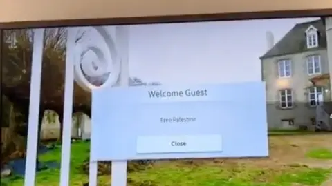 A pop up window on a hotel room TV saying "welcome guest - Free Palestine" with a button to "close" the window if selected on the TV remote.